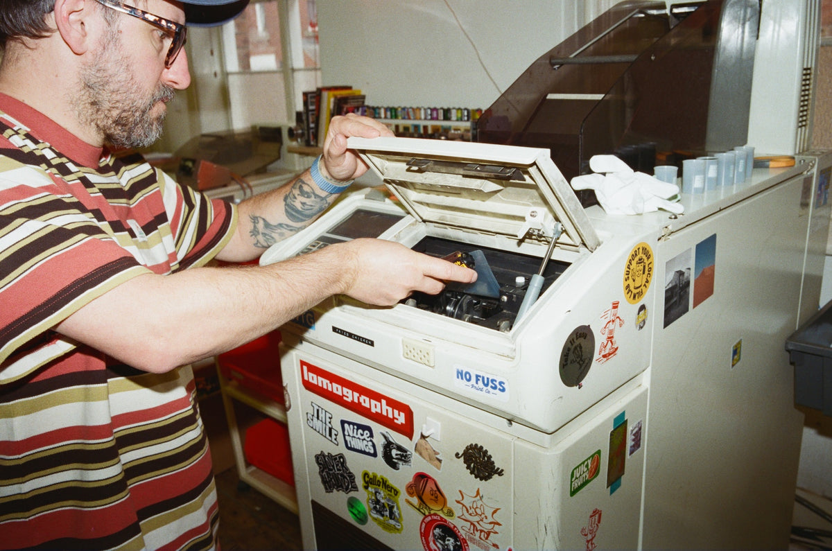 Man interacting with a film photography processing machine in a film lab setting