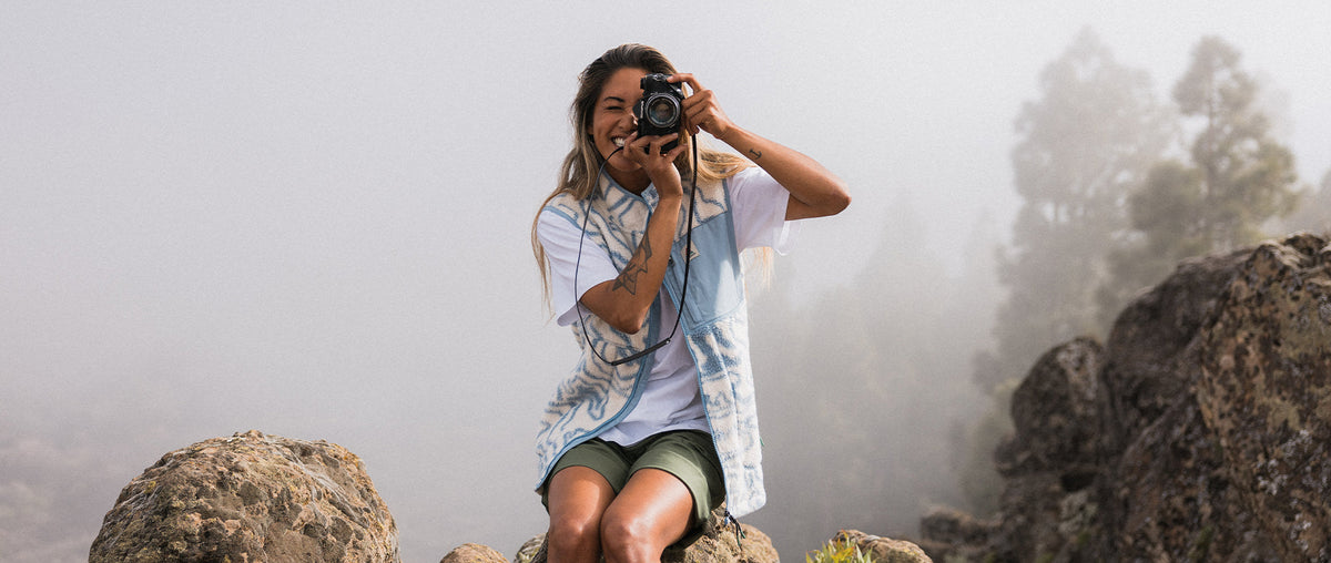 A woman in a fleece taking a photo on a mountain ridge